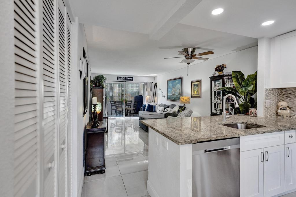 A kitchen with granite countertops and white cabinets overlooks a living area with tile floors — 3060 Holiday Springs Boulevard # 106, Margate FL 33063, MARGATE, FL