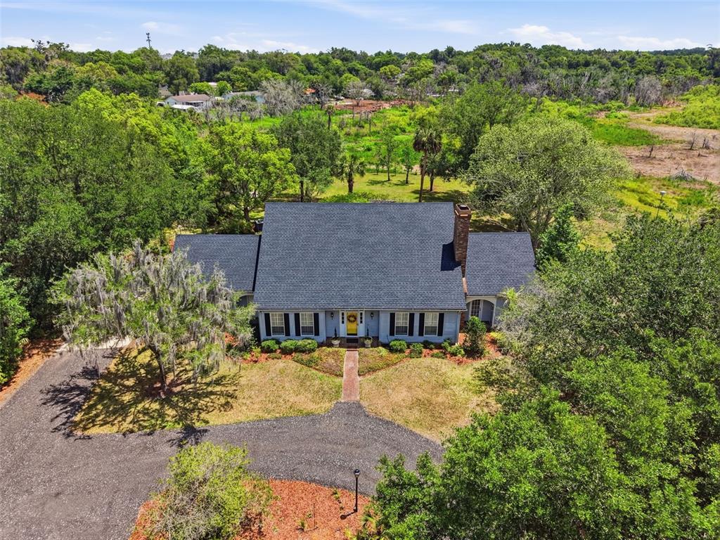 An aerial view shows a house with a dark roof surrounded by trees and grass — 1245 WESTOAK DRIVE, DELAND, FL