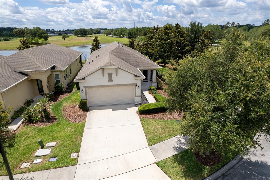 An aerial view shows a single-story house with a two-car garage and a backyard pond — 3300 SAGEBRUSH STREET, HARMONY, FL