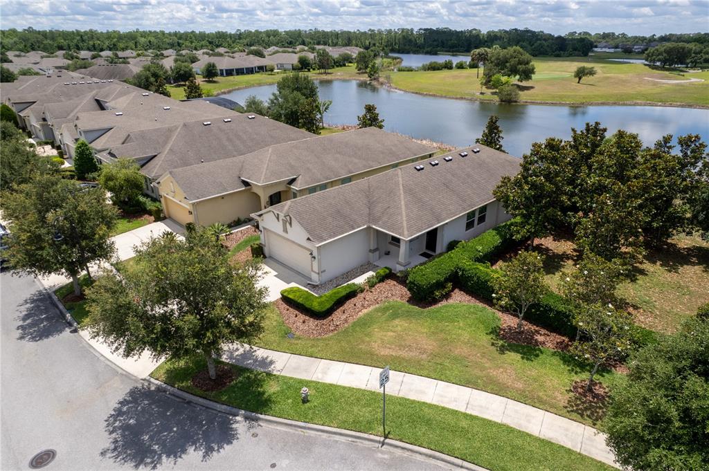 An aerial view shows a suburban house with a garage, lawn, and a nearby pond — 3300 SAGEBRUSH STREET, HARMONY, FL