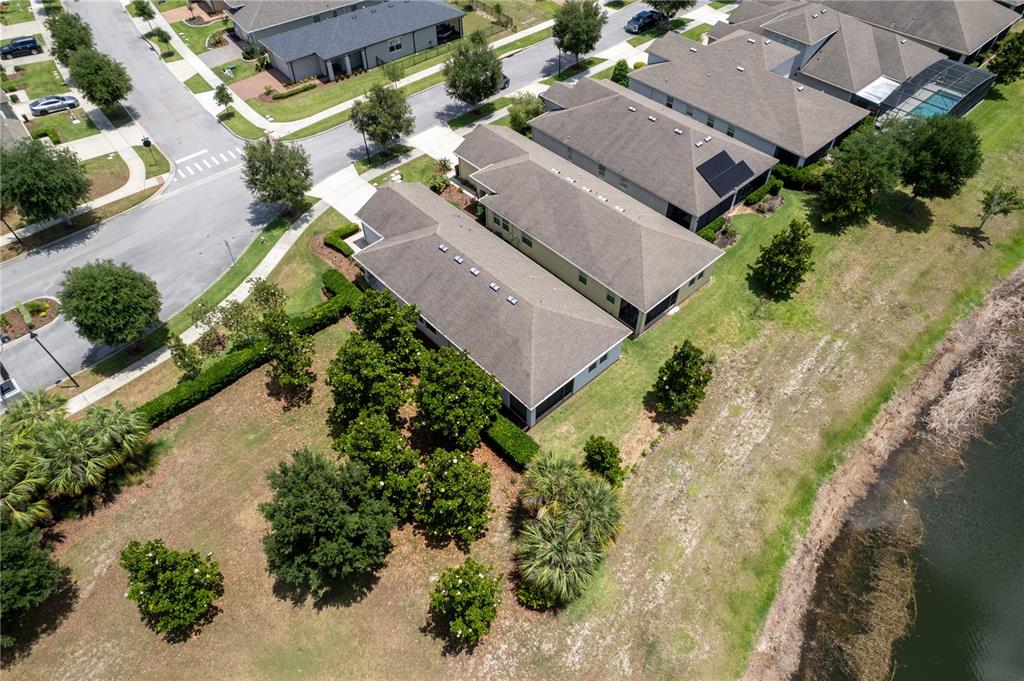 An aerial view shows a row of suburban houses situated next to a small pond — 3300 SAGEBRUSH STREET, HARMONY, FL