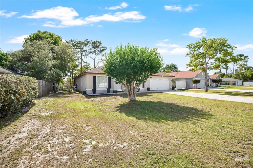 A single-story house with a white garage, a large front tree, and a grassy yard — 1779 MEREDITH AVENUE, DELTONA, FL