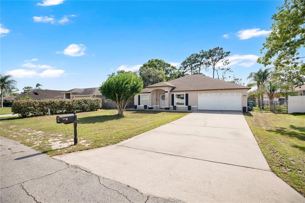 A single-story house with a beige exterior, a two-car garage, and a concrete driveway — 1779 MEREDITH AVENUE, DELTONA, FL