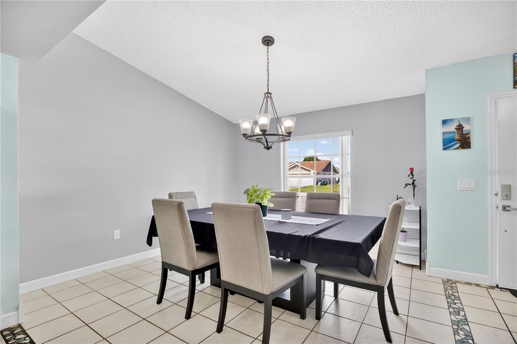 A dining room features a dark-clothed table, six upholstered chairs, and a central chandelier — 1779 MEREDITH AVENUE, DELTONA, FL