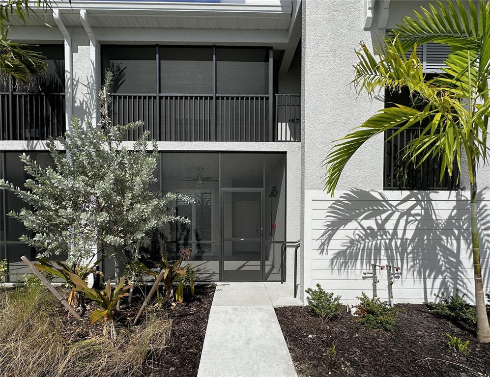 A concrete walkway leads to the screened-in entrance of a multi-story residential building — 14221 HERITAGE LANDING BOULEVARD UNIT 2017, PUNTA GORDA, FL