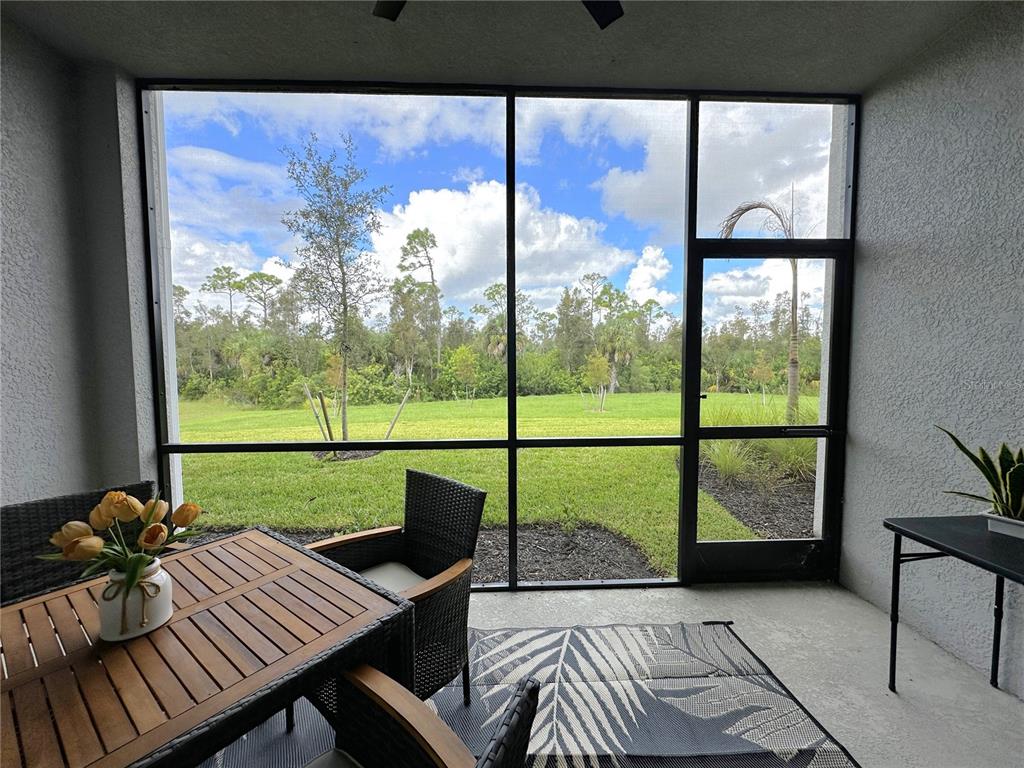 A screened-in patio features a dining set, a patterned rug, and views of a grassy yard — 14221 HERITAGE LANDING BOULEVARD UNIT 2017, PUNTA GORDA, FL
