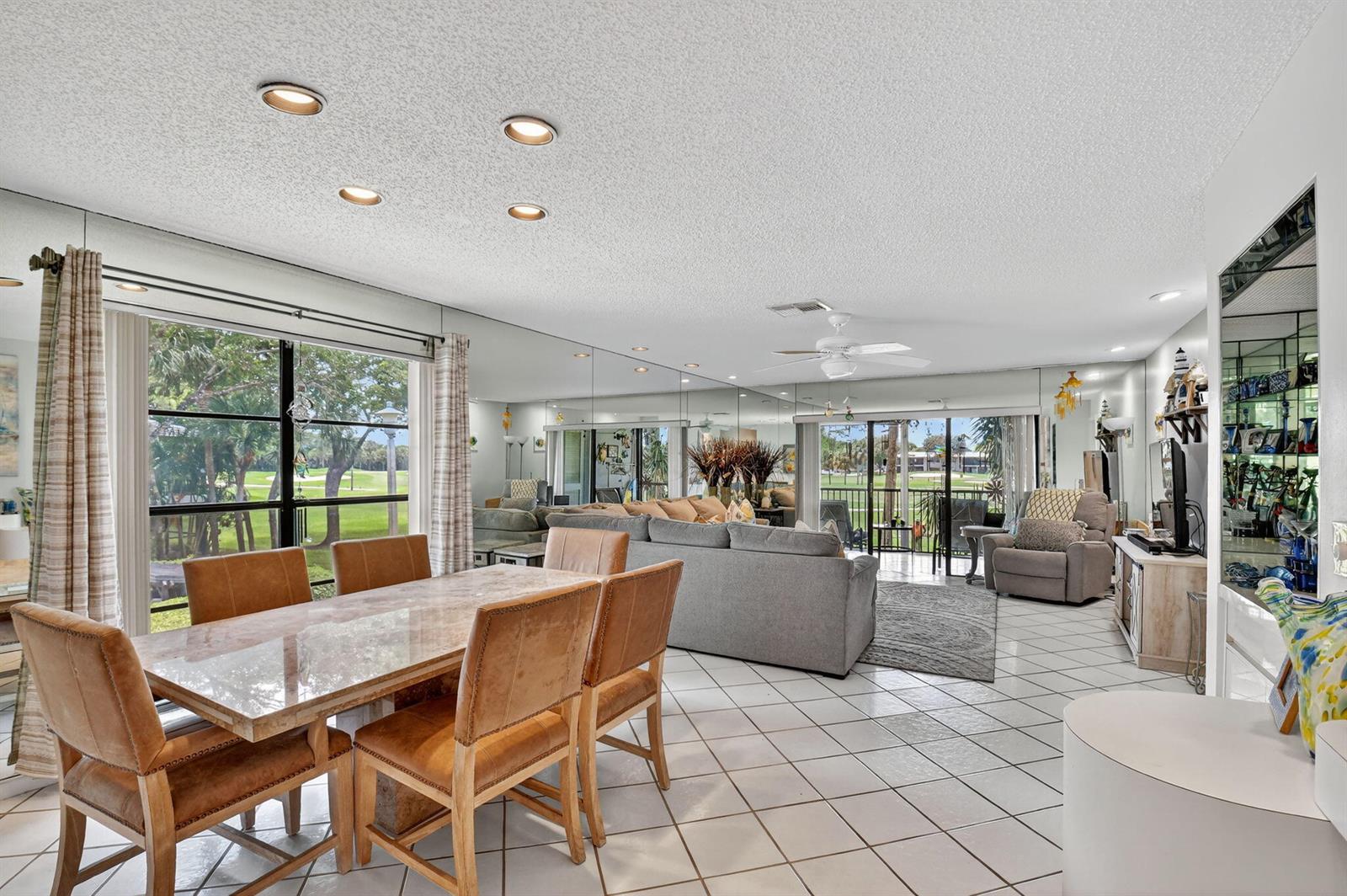 A dining and living area features tiled floors, mirrored walls, and a view of a golf course — 7 Southport Lane # B, Boynton Beach FL 33436, BOYNTON BEACH, FL