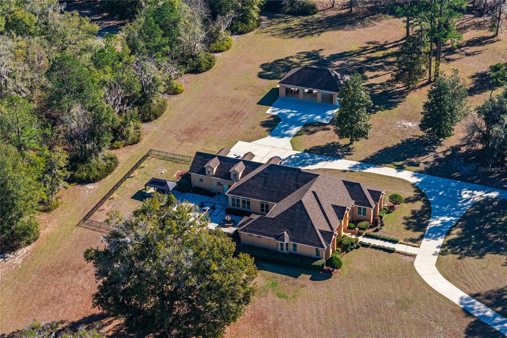 An aerial view shows a large house with a detached garage on a wooded lot — 573 SE NATURE DRIVE, LAKE CITY, FL