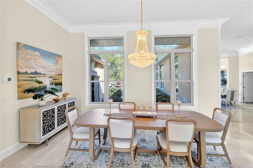 A dining room features a wooden table, six chairs, a crystal chandelier, and large windows — 573 SE NATURE DRIVE, LAKE CITY, FL