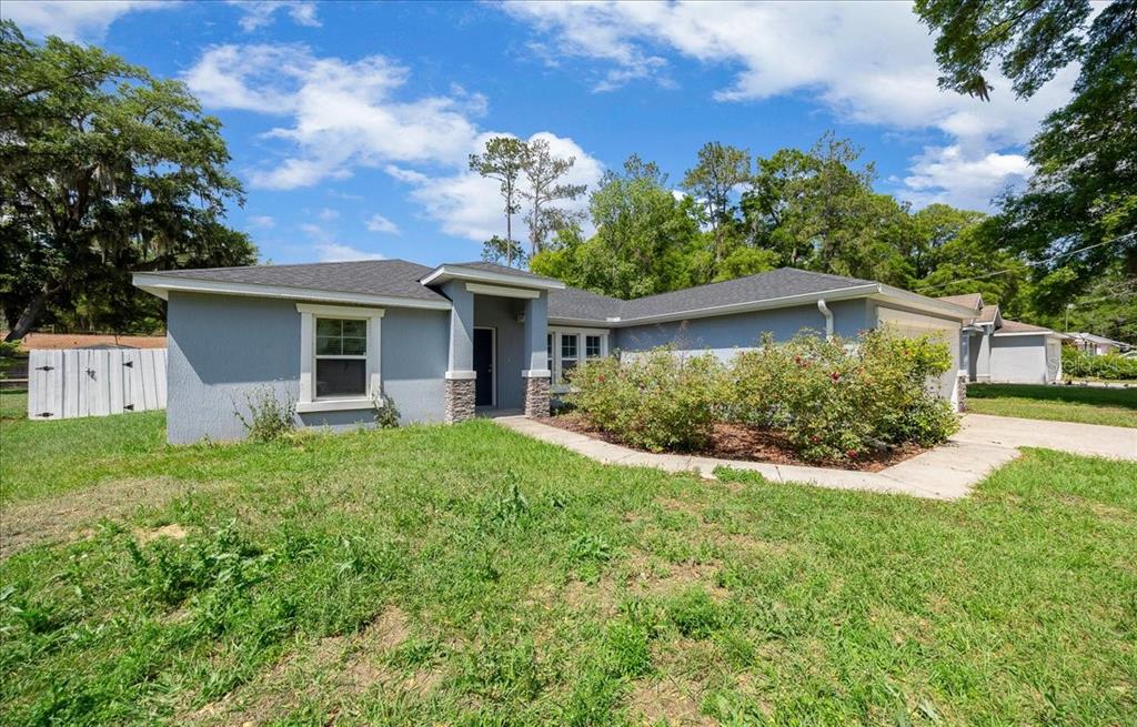 A single-story gray house with a stone-accented entryway and a front lawn — 5488 NW 61ST AVENUE, OCALA, FL