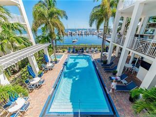 An outdoor swimming pool sits on a patio overlooking a marina with docked boats — 815 NW Flagler Avenue # 302, Stuart FL 34994, STUART, FL