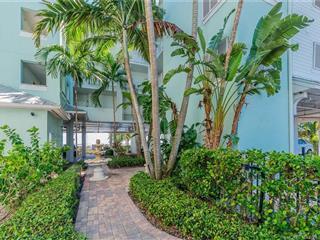 A paved walkway leads past a tiered fountain toward a light blue multi-story building — 815 NW Flagler Avenue # 302, Stuart FL 34994, STUART, FL