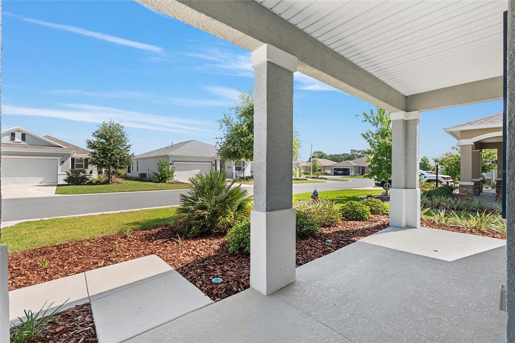 A view from a covered concrete front porch looking out toward a suburban residential street — 8837 SW 79TH LOOP, OCALA, FL