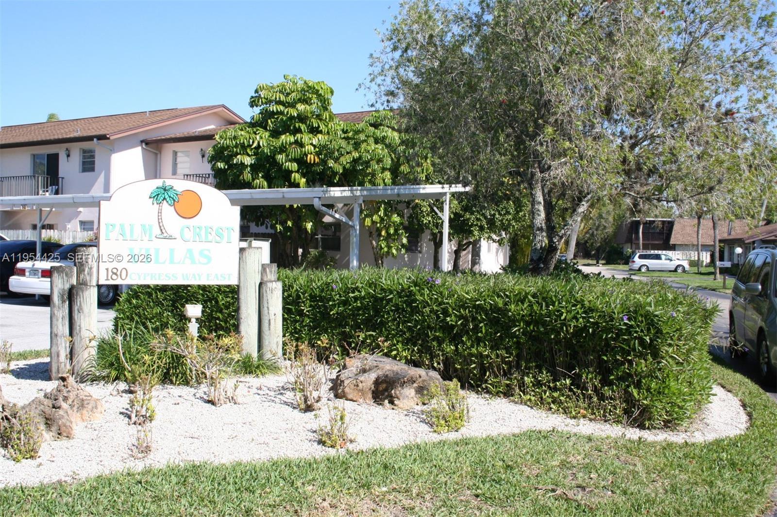A sign for Palm Crest Villas stands in front of a building and landscaping — 180 E Cypress Way # E230, Naples FL 34110, NAPLES, FL
