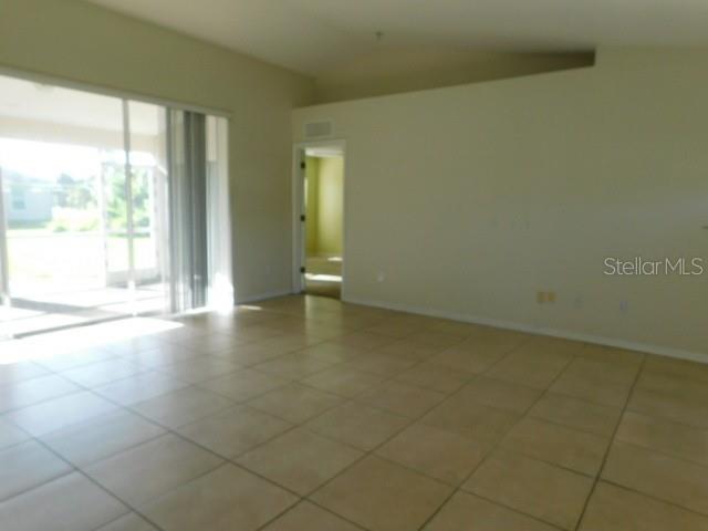 An interior view of a living area with tile flooring, vaulted ceilings, and sliding glass doors — 3034 BROCKTON STREET, NORTH PORT, FL