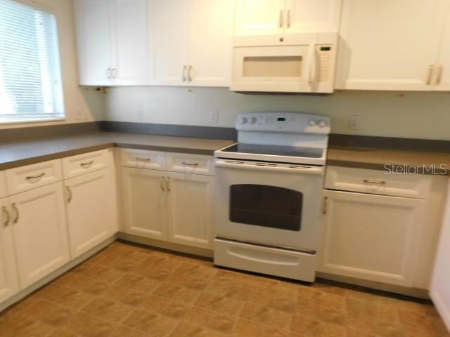 A kitchen features white cabinets, a white stove, and a window with blinds — 3034 BROCKTON STREET, NORTH PORT, FL