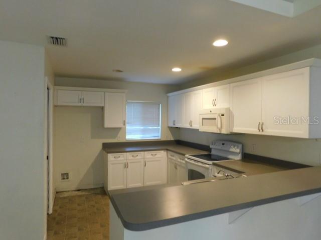 A kitchen with white cabinets, gray countertops, and a white oven — 3034 BROCKTON STREET, NORTH PORT, FL