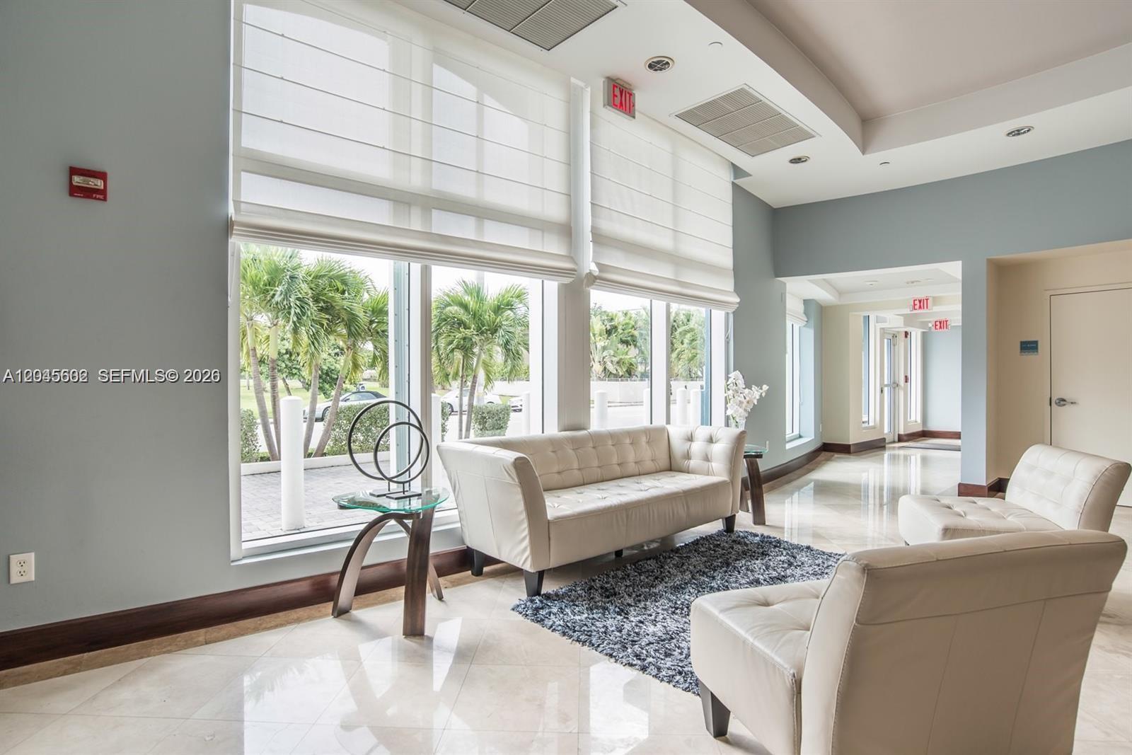 A modern lobby features white tufted furniture, a dark rug, and large windows with blinds — 7600 Collins Ave # 712, Miami Beach FL 33141, MIAMI BEACH, FL