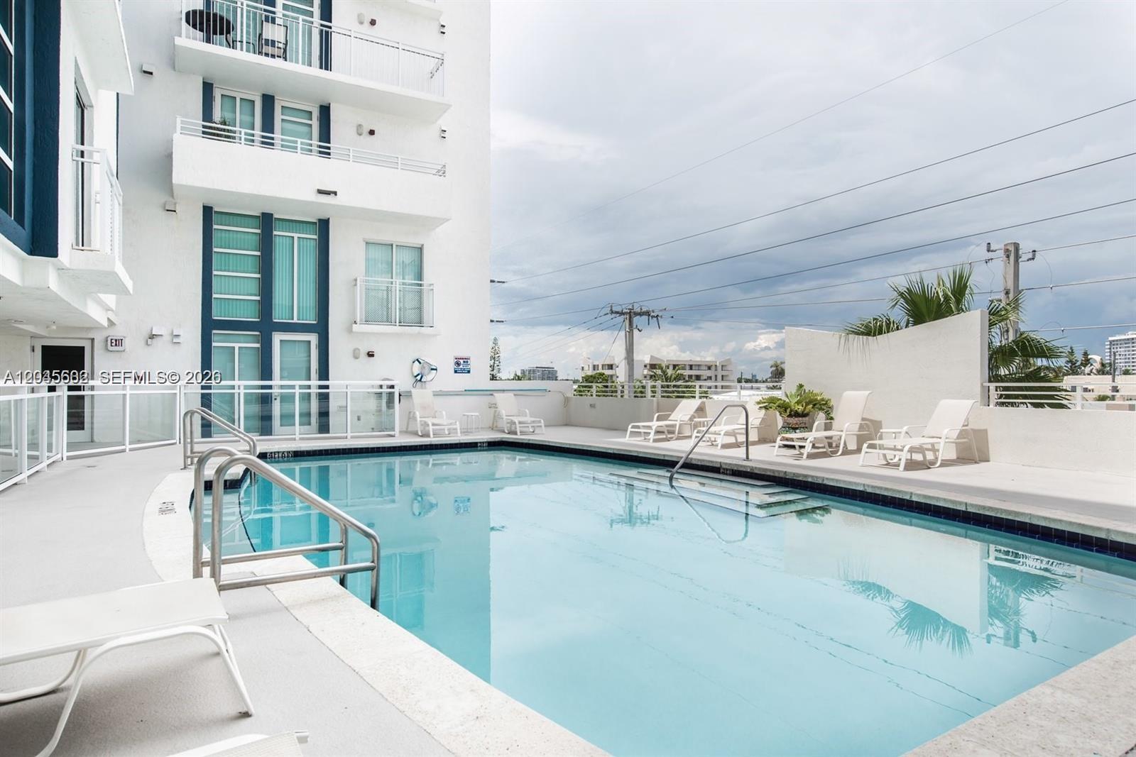 A rectangular swimming pool is surrounded by lounge chairs on a white concrete deck — 7600 Collins Ave # 712, Miami Beach FL 33141, MIAMI BEACH, FL