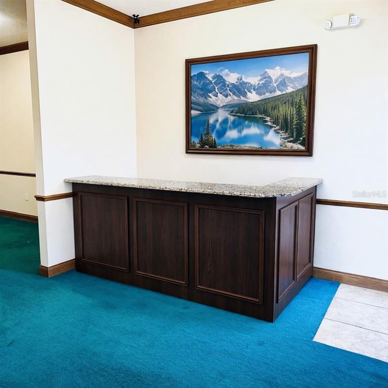 A dark wood reception desk with a granite countertop sits against a wall with artwork — 5115 S LAKELAND DRIVE, LAKELAND, FL
