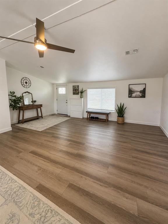 A spacious room features wood-look flooring, a ceiling fan, a white door, and a bench — 3627 TOM MATTHEWS ROAD, LAKELAND, FL