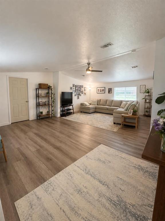 A spacious living room features light wood-look flooring, a sectional sofa, and a ceiling fan — 3627 TOM MATTHEWS ROAD, LAKELAND, FL