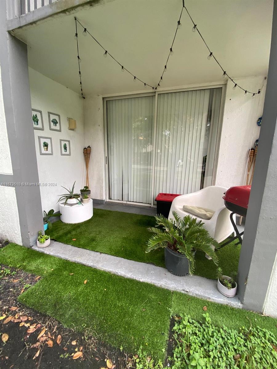 A patio features artificial turf, a white chair, a grill, and wall-mounted succulent art — 4440 NW 107th Ave # 7, Doral FL 33178, DORAL, FL