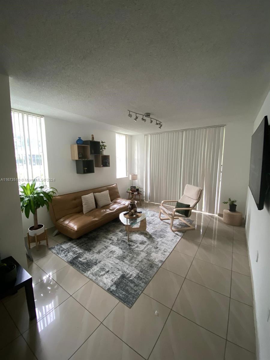A living room features a tan sofa, an armchair, a patterned rug, and tile flooring — 4440 NW 107th Ave # 7, Doral FL 33178, DORAL, FL