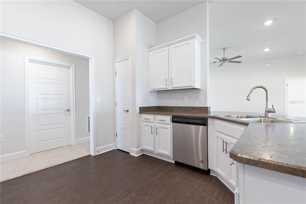 A kitchen with white cabinets, stainless steel dishwasher, dark countertops, and dark wood-look flooring — 39 BIRCHWOOD DRIVE, PALM COAST, FL