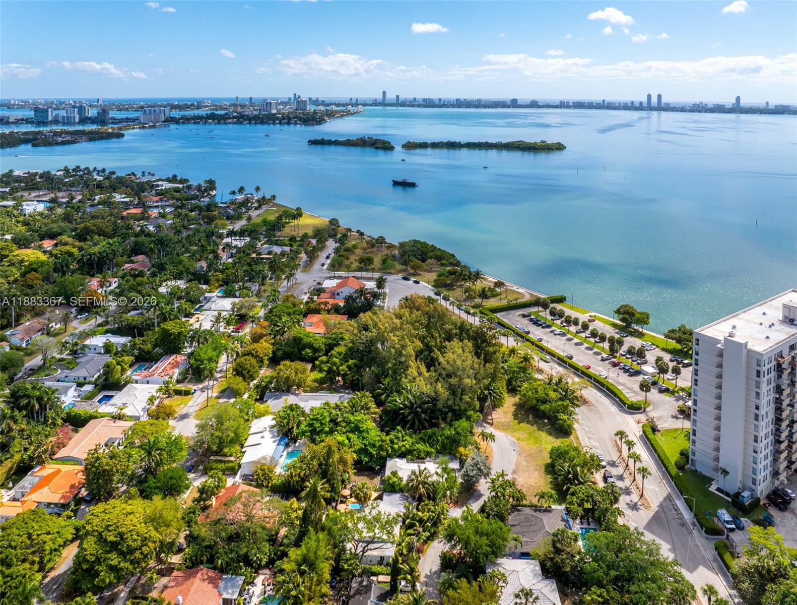 An aerial view shows a coastal neighborhood with houses, trees, a parking lot, and water — 860 NE 70th St, Miami FL 33138, MIAMI, FL