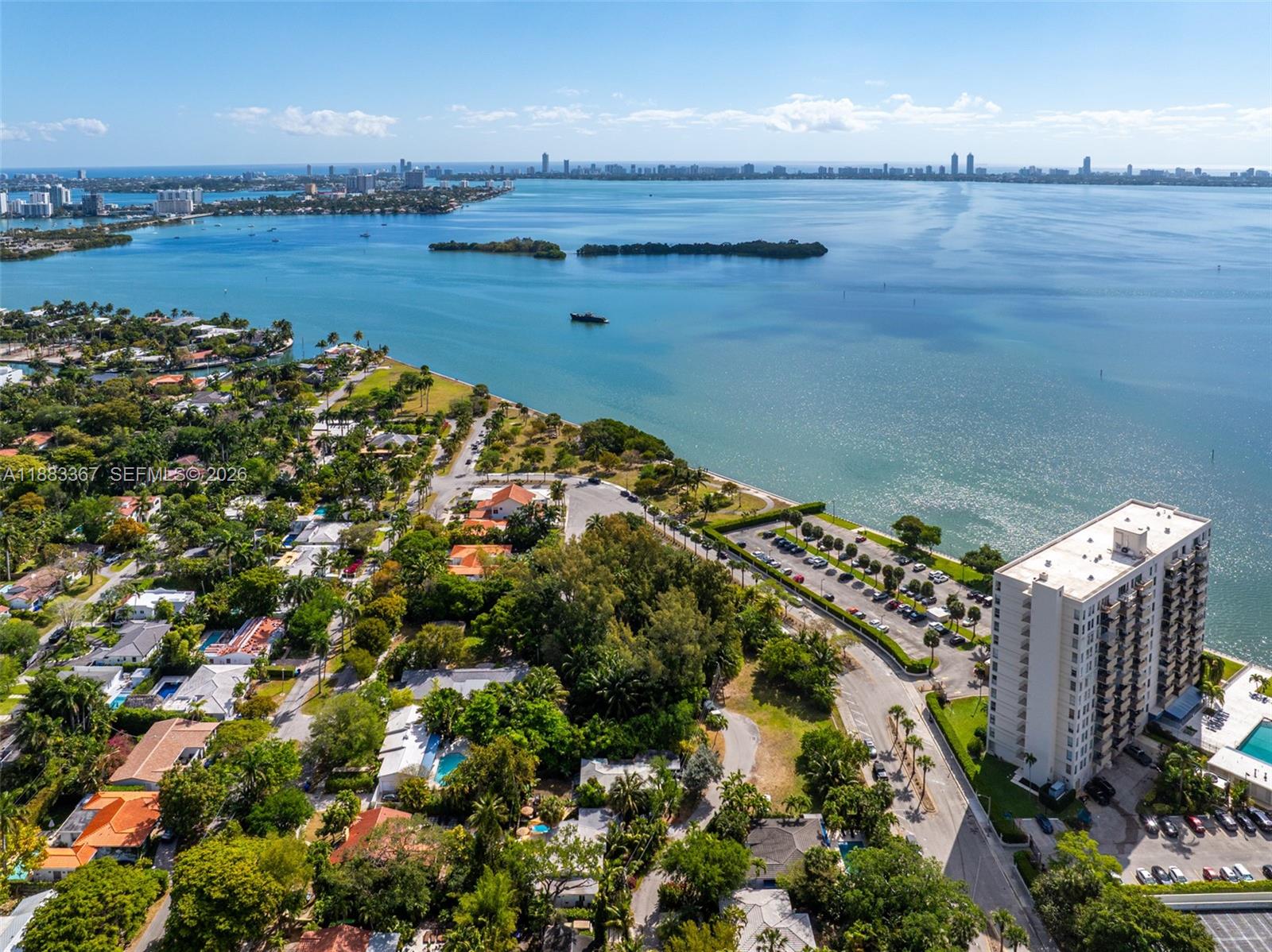An aerial view shows a coastal neighborhood with a tall apartment building and waterfront — 860 NE 70th St, Miami FL 33138, MIAMI, FL