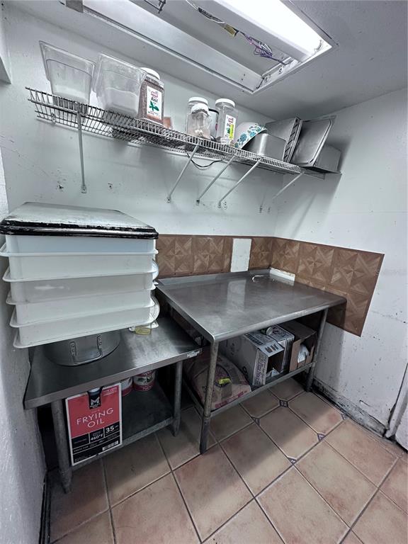 A commercial kitchen prep area features stainless steel tables, wire shelving, and tiled flooring — 9852 E COLONIAL DRIVE, ORLANDO, FL