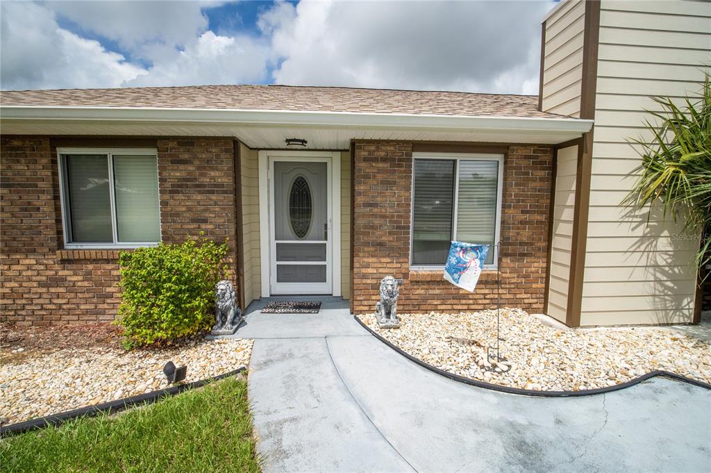 A brick and siding house exterior features a front door with a screen and two lions — 751 VEGA COURT NE, PALM BAY, FL