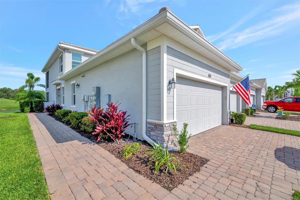 A side view of a house exterior featuring a paved driveway, garage, and landscaping — 947 TIDEWATER SHORES LOOP, BRADENTON, FL
