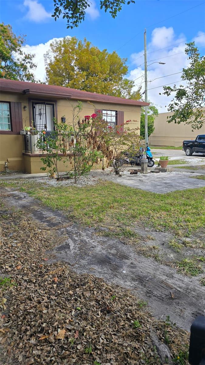 A tan house with a front porch, a small yard, and a parked blue scooter — 6910 NW 5th Pl, Miami FL 33150, MIAMI, FL