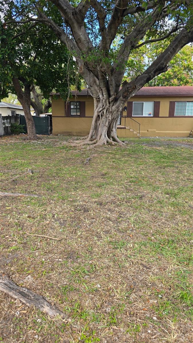 A large tree with exposed roots stands in the front yard of a brown house — 6910 NW 5th Pl, Miami FL 33150, MIAMI, FL
