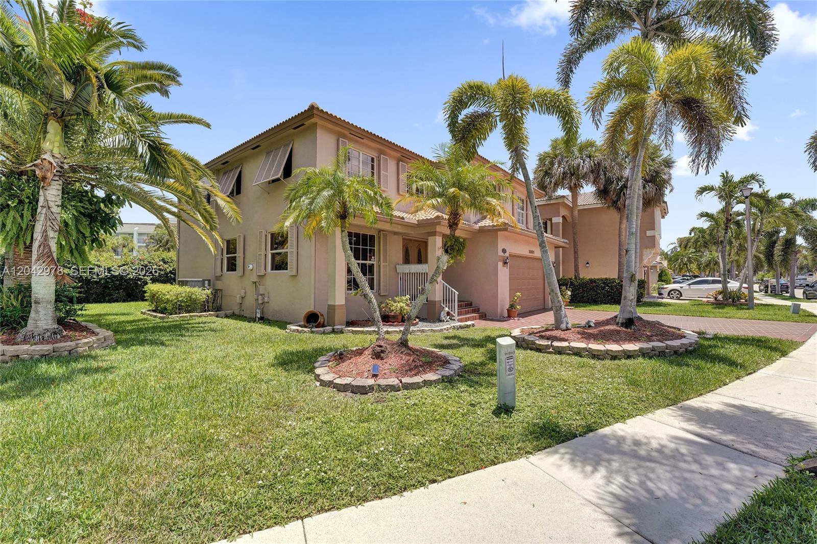 A two-story suburban house features a tiled driveway, a garage, and palm trees — 16091 La Costa Dr, Weston FL 33326, WESTON, FL