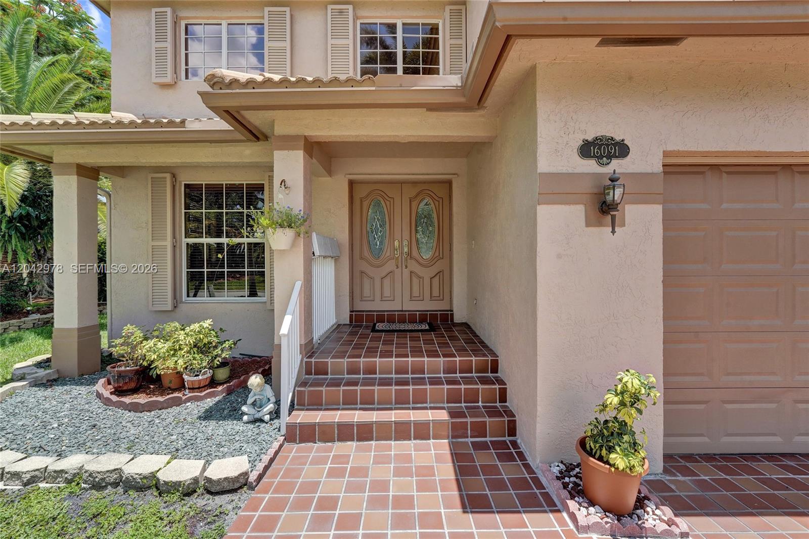 The exterior of a two-story beige house features a side yard, palm tree, and shutters — 16091 La Costa Dr, Weston FL 33326, WESTON, FL
