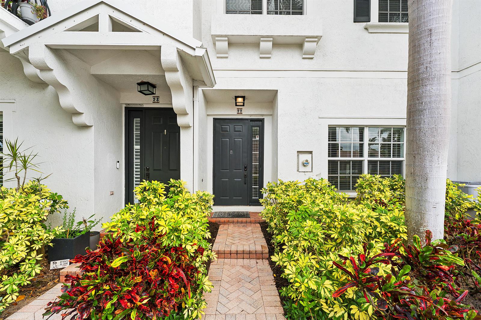 The exterior of a two-story white building features two dark front doors with numbered plaques — 295 NE 5th Avenue # 22, Delray Beach FL 33483, DELRAY BEACH, FL