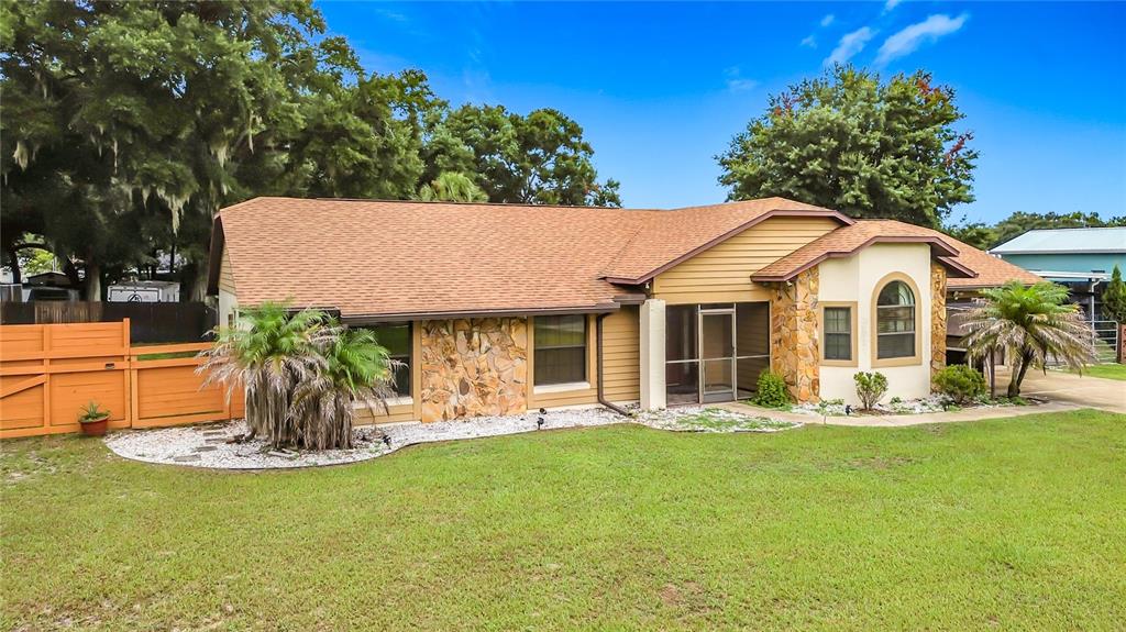A covered patio with a dining set overlooks a screened-in swimming pool and backyard — 634 GRAPE AVENUE, ST CLOUD, FL