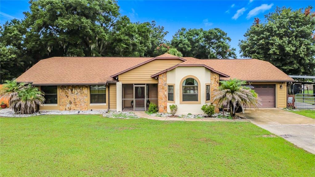 A screened-in swimming pool with a tiled deck and a statue water feature — 634 GRAPE AVENUE, ST CLOUD, FL