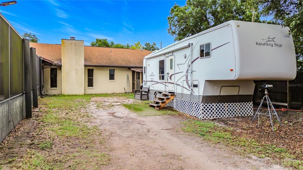 A metal storage building with a shipping container door and a white sliding door exterior — 634 GRAPE AVENUE, ST CLOUD, FL