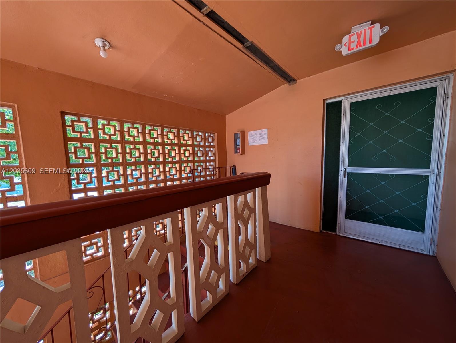An outdoor hallway features a decorative concrete screen wall, a red floor, and an exit door — 19080 NE 3rd Ct # 311, Miami FL 33179, MIAMI, FL