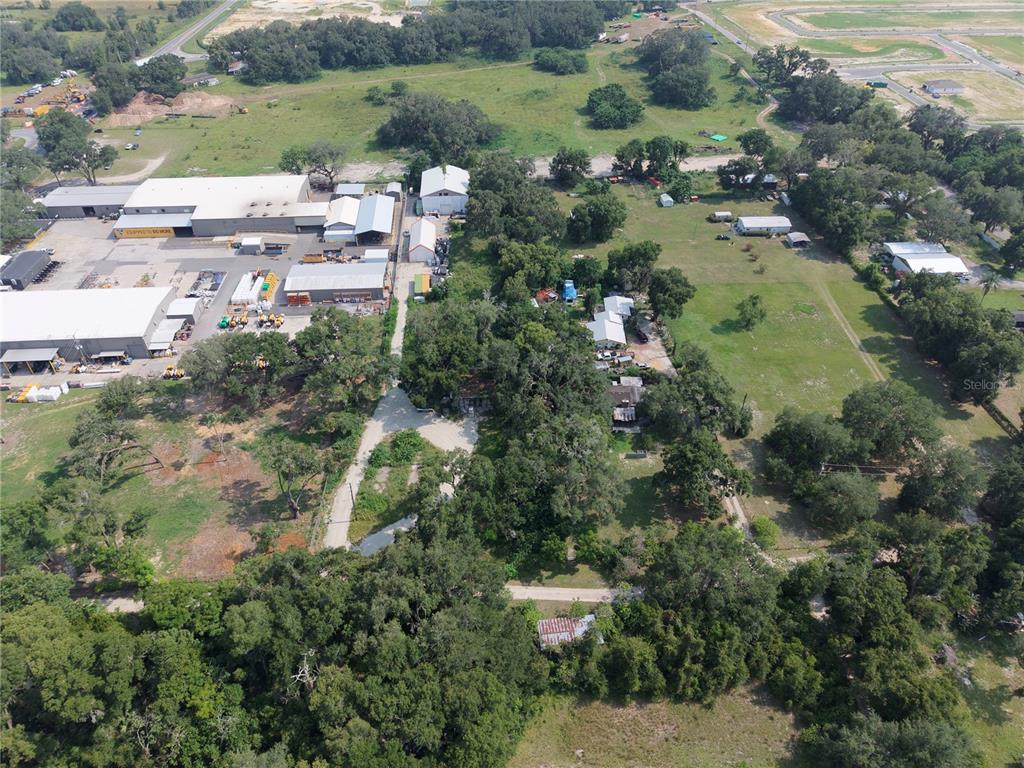 An aerial view shows a large industrial complex adjacent to a wooded residential property — 3350 4TH STREET, OKAHUMPKA, FL