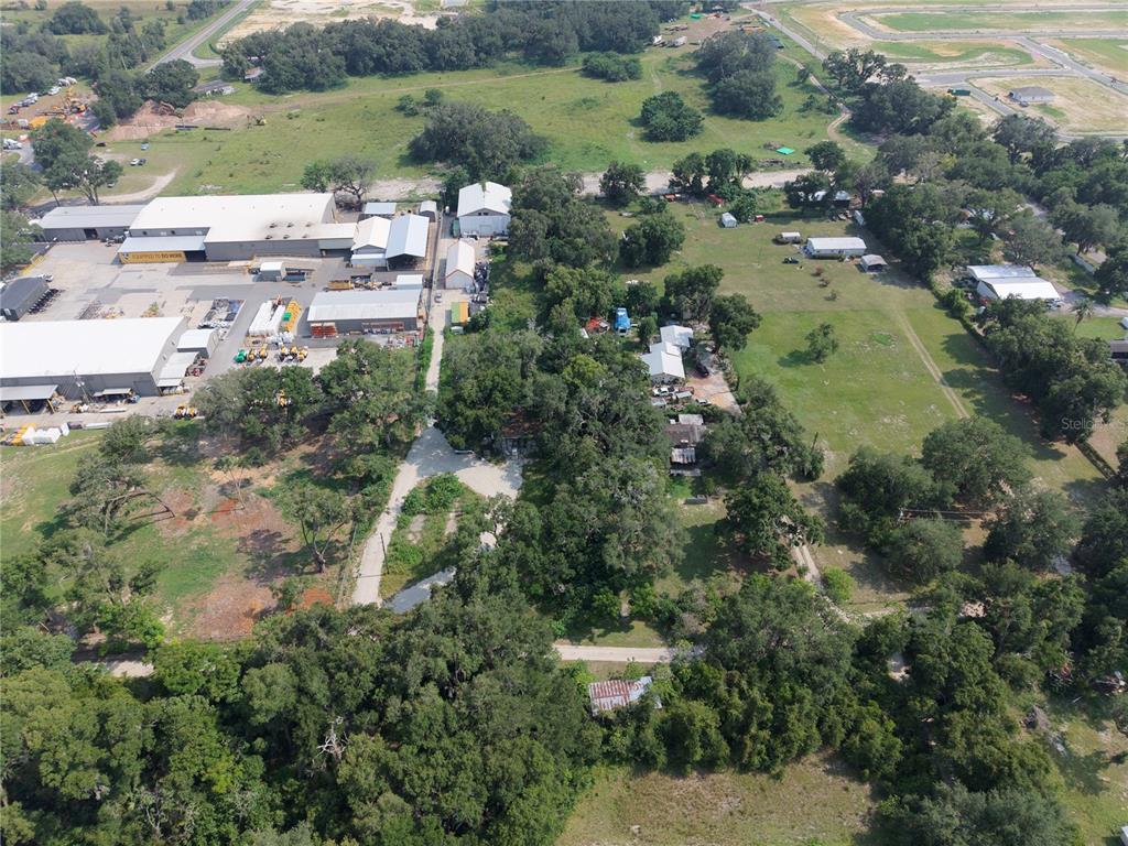 An aerial view shows a large industrial complex adjacent to a wooded residential property — 3350 4TH STREET, OKAHUMPKA, FL