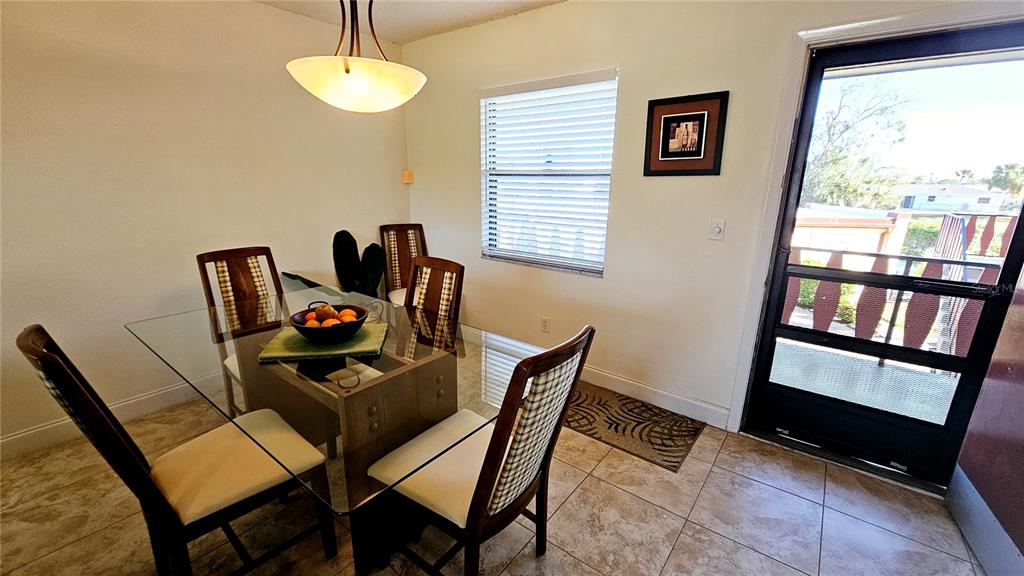 A dining area features a glass-topped table, four chairs, tile flooring, and a glass door — 84 BOUNDARY BOULEVARD UNIT 169, ROTONDA WEST, FL