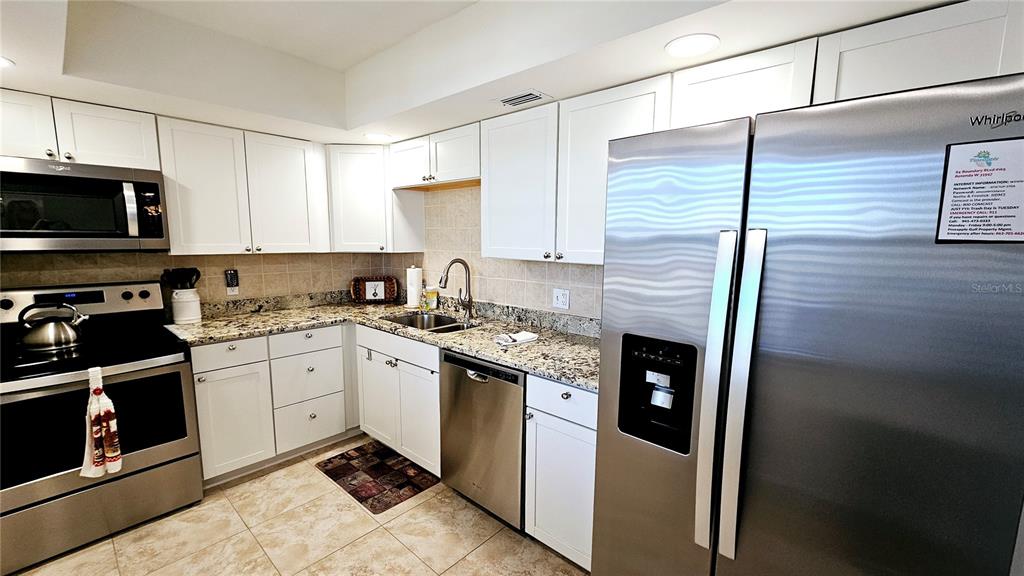 A kitchen features white cabinets, granite countertops, and stainless steel appliances — 84 BOUNDARY BOULEVARD UNIT 169, ROTONDA WEST, FL