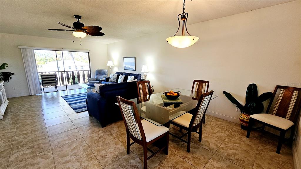 An open-concept living and dining area features tile flooring, a glass dining table, and a balcony — 84 BOUNDARY BOULEVARD UNIT 169, ROTONDA WEST, FL