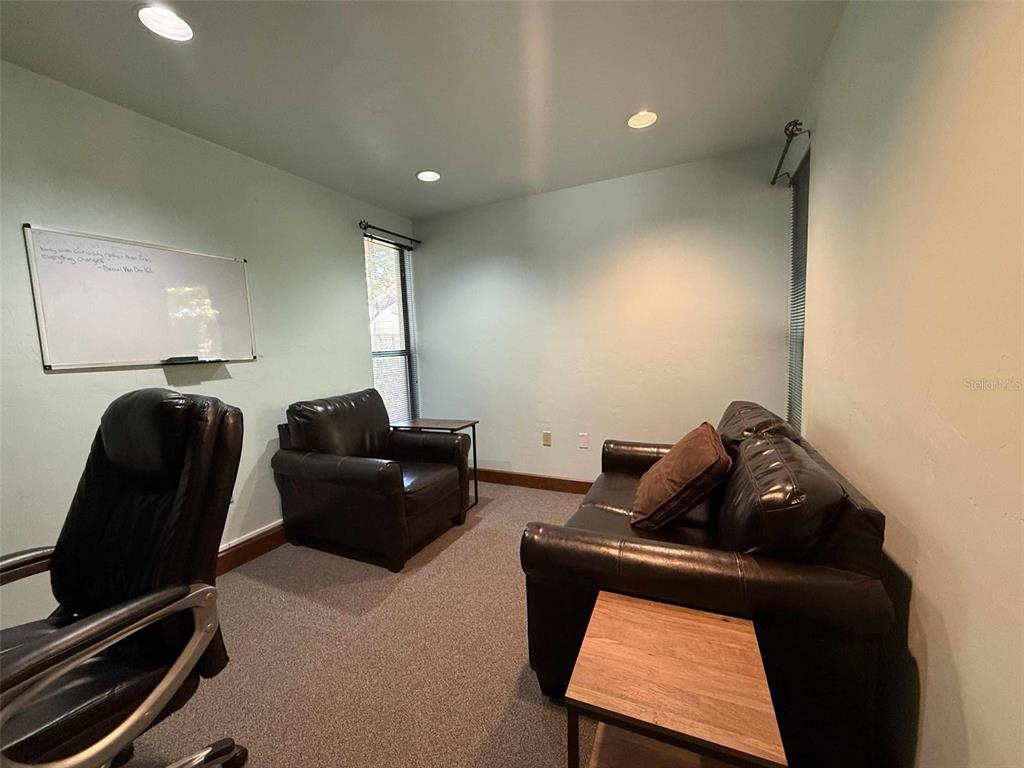 A home office features a leather sofa, an armchair, a whiteboard, and carpeted flooring — 2833 NW 41ST STREET UNIT 140 Room B, GAINESVILLE, FL