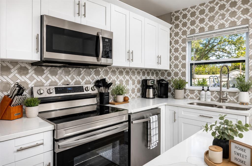 A modern kitchen features white cabinets, stainless steel appliances, and a patterned tile backsplash — 1000 8TH AVENUE SW, LARGO, FL